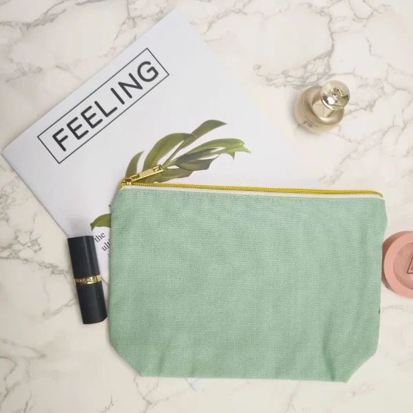 A light green canvas makeup bag with a gold zipper, showcasing customizable design options