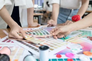 A group of people gathered around a table with numerous color swatches, discussing color options and printing methods to represent the customizable nature of Yanxin Bag's products.