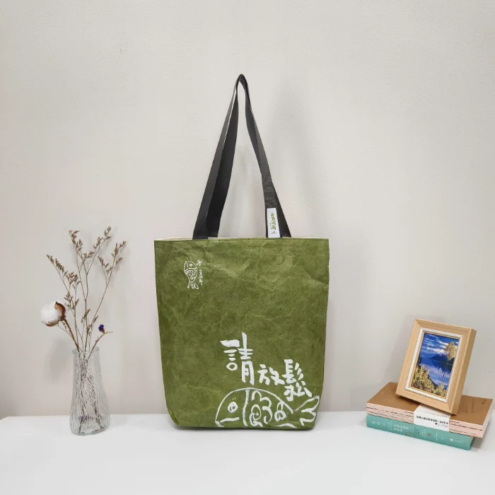 A dark green plain DuPont paper tyvek bag with black handles, featuring a custom-printed logo, showcasing customizable options for size, material, and logo