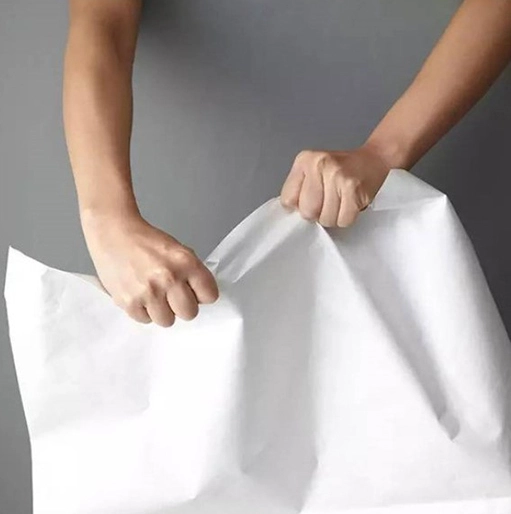 Tyvek Drawstring Bags: 4 Irresistible Reasons to Love Them 2 A pair of hands forcefully tearing a piece of DuPont paper (Tyvek) fabric to demonstrate its tear resistance