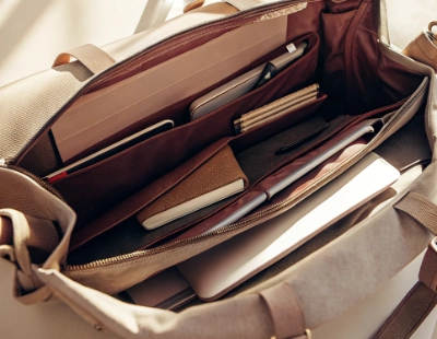 A realistic tote bag image showcasing why tote bags are so popular, with a wide open top revealing items such as a laptop, books, and a pencil case.