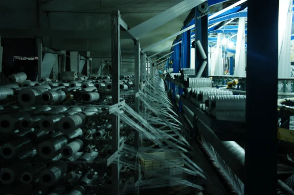 PP Woven Fabric Manufacturing Process - A key step in the production of PP woven fabric, where polypropylene strips are woven into a mesh-like structure.