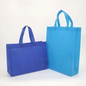 Two blue non-woven tote bags standing upright on a white background, showcasing different sizes and hues, customizable in size, material, style, and printing.