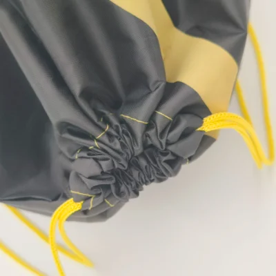 Detailed cinch closure of a black and yellow polyester drawstring backpack, ideal for cleaning tips in “How to Clean Polyester Bags? A Complete Guide”, customizable in size, material, style, and printing.