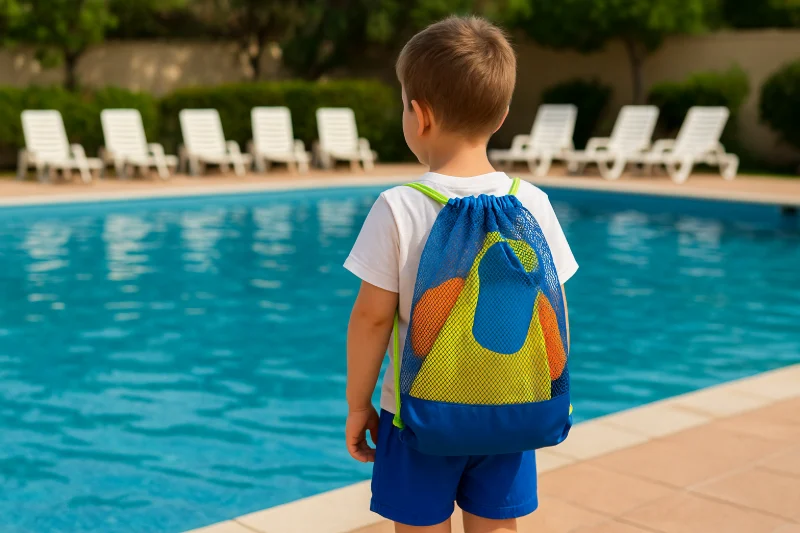 A young boy wearing a light mesh swim bag on the beach, designed for kids' swimming lessons and summer water activities