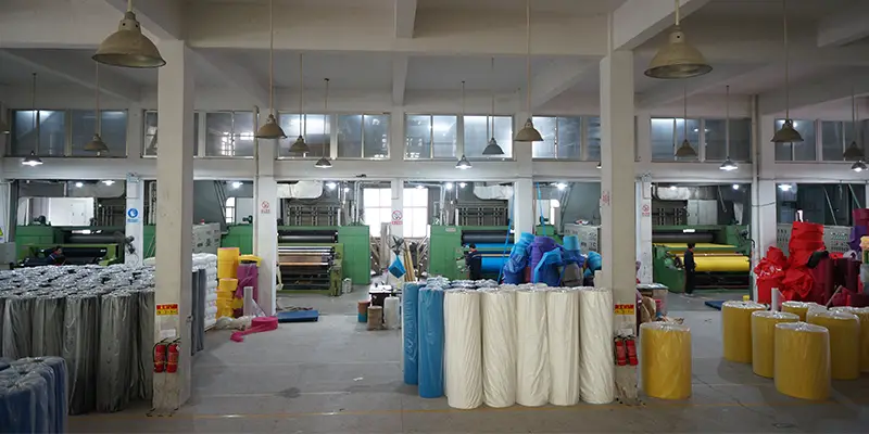 nonwoven fabric rolls and machines inside a factory shown in What Are the Main Types of Nonwoven Fabric