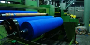 PP spunbond nonwoven fabric roll being processed on industrial machine shown in What Is PP Spunbond Nonwoven Fabric