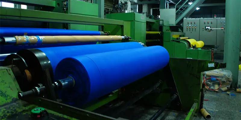 PP spunbond nonwoven fabric roll being processed on industrial machine shown in What Is PP Spunbond Nonwoven Fabric