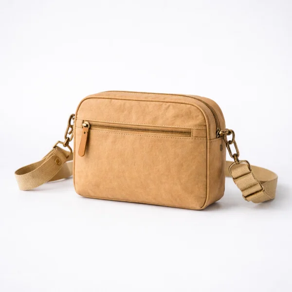 A compact washable kraft crossbody bag with a zippered main compartment and an adjustable strap on a light background.