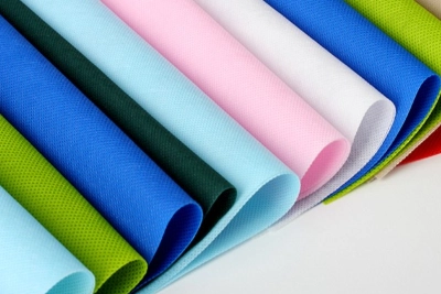 A close-up view of several colorful rolled sheets used to illustrate what is non woven fabric and its textured material surface.