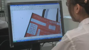 A person reviewing a brochure on a computer screen while working, illustrating how to efficiently choose a custom bag manufacturer in China.