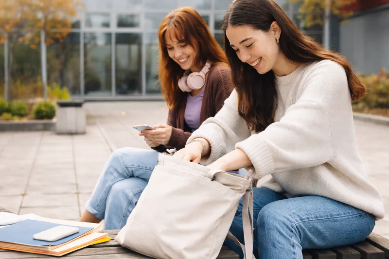 Two students outdoors using a cotton tote bag, illustrating Why Are Cotton Bags Becoming Popular in Schools and Kids Events.