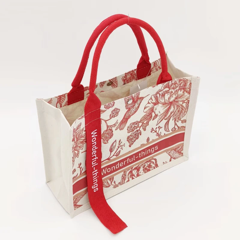 Canvas tote bag with red handles and snap button closure, shown in a structured side view.