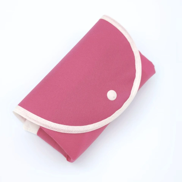 How to Choose the Right Foldable Bag for Your Business? A pink foldable bag is shown in a compact folded form with a snap closure.