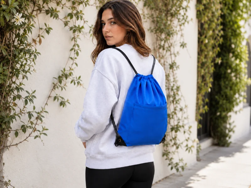Why Custom Printed Drawstring Backpacks Are Perfect Promotional Giveaways showing a blue drawstring backpack worn outdoors with shoulder cords.