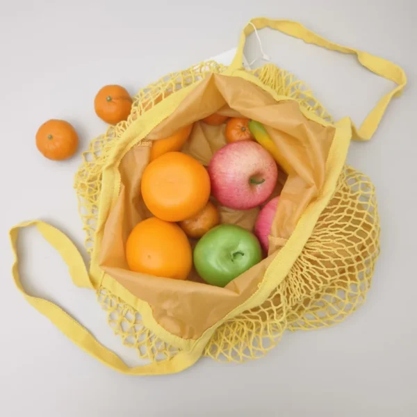Open mesh grocery tote bag filled with fruits, showing material texture and reinforced stitching