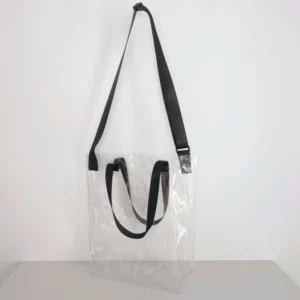 A clear crossbody bag with black straps displayed against a white background, illustrating Top-Selling Clear Bag Styles for B2B in 2026.