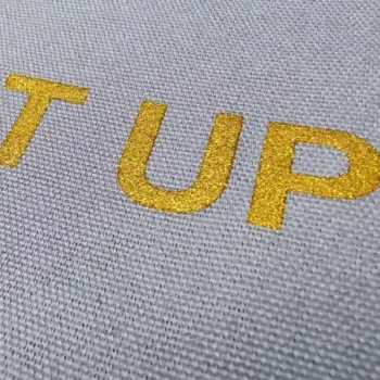 Glitter logo printing applied on fabric, showing a bright gold sparkling logo effect for custom bags.